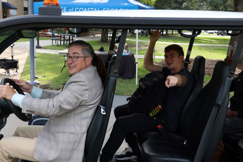 College President Dr. Johnny Evans Jr. drives students in a golf cart to their classes.